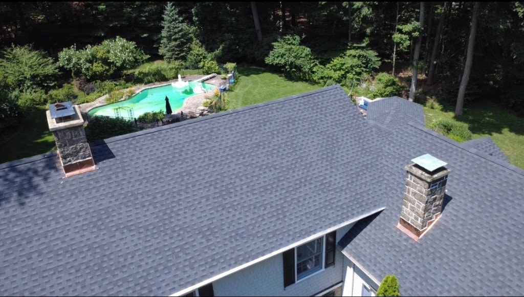 Aerial view of completed asphalt shingle roof with stone chimneys in Fairfield County, CT