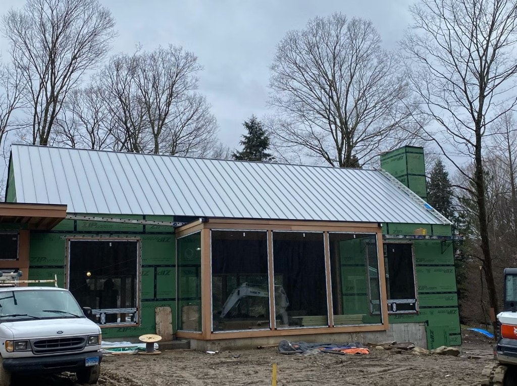 Standing seam metal roof installation in progress on a new Connecticut home build