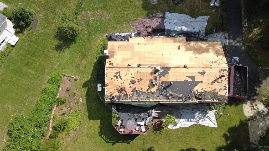 Before — aerial view of roof tear-off with tarps protecting the property during replacement